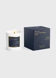 a white candle next to a box on a gray background with the words maison krokhans