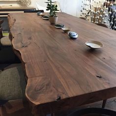 a wooden table with plates on it in a room filled with chairs and vases