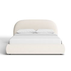 a white bed with two pillows on top of it and a night stand next to it