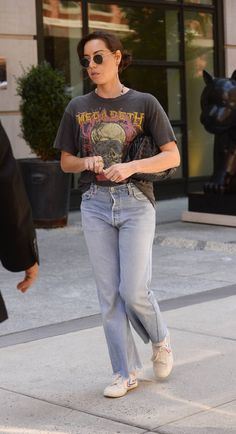 a woman walking down the street with her hand in her pocket and wearing sunglasses on