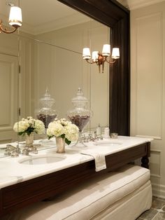 a bathroom with two sinks, mirrors and flowers in vases on the counter top