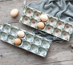 two trays filled with eggs sitting on top of a wooden table next to a cloth