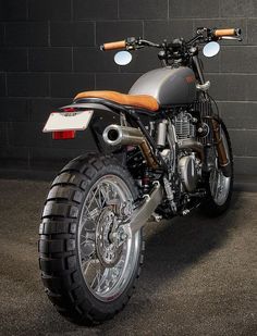 a motorcycle parked in front of a brick wall with two lights on it's side