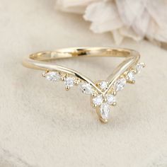 a close up view of a gold ring with white stones on it and a flower in the background