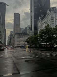 an empty city street in the rain with tall buildings on either side and dark clouds overhead