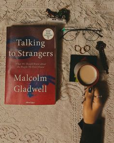 a person holding a coffee cup in front of a book on a lace tablecloth