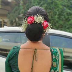 a woman with flowers in her hair standing next to a car and wearing a green dress