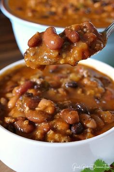 a spoon full of chili and beans in a white bowl