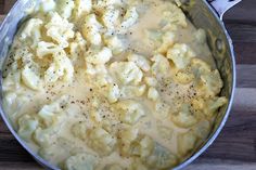 a white bowl filled with mashed potatoes covered in cheese and green onion garnish