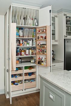 an open refrigerator in a white kitchen with lots of cupboards and drawers on the door