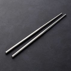 two chopsticks sitting next to each other on a black surface with space for text