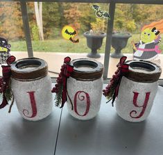 three mason jars decorated with christmas decorations and the word joy are sitting on a window sill