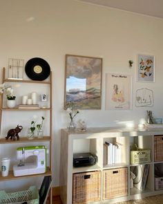 a room with shelves, baskets and pictures on the wall next to a sewing machine