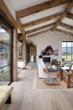 a living room filled with furniture and large windows next to a wooden floored wall