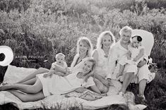 a black and white photo of a family sitting on a blanket in the middle of a field