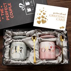 two coffee mugs in a gift box with gold spoons and a greeting card