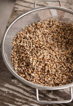 a metal strainer filled with seeds on top of a wooden table