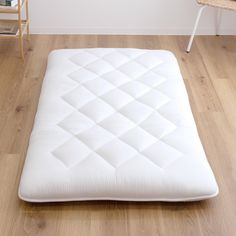 a white mattress sitting on top of a hard wood floor next to a wooden table