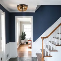 an entryway with blue walls and white trim on the stairs is flanked by a wooden banister