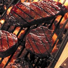 steaks are cooking on the grill and being grilled with tongs next to it