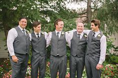 a group of young men standing next to each other in front of trees and flowers