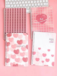 three notebooks with hearts on them next to a keyboard