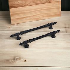 two black iron handles on a wooden table next to a wood box and other items