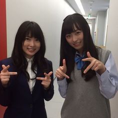 two young women standing next to each other giving the peace sign with their hands in front of them