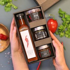 a person holding an open box with sauces and condiments in it on a table