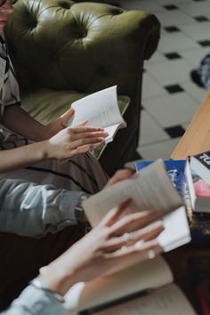 two people sitting on a couch reading books together and one person holding an open book