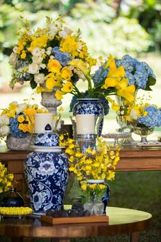 a table topped with vases filled with yellow and blue flowers