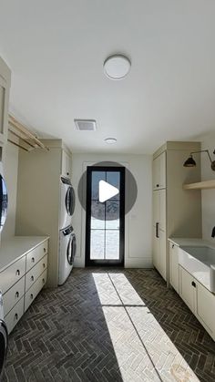 an empty laundry room with washers, dryer and cabinets on the floor in front of a black door