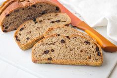 slices of bread sitting on top of a cutting board next to an orange handled knife