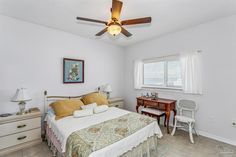 a bedroom with a bed, desk and ceiling fan