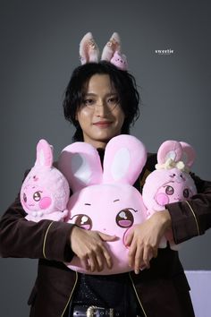 a woman holding two stuffed animals in her hands and wearing bunny ears on their head