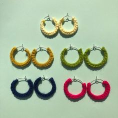 small crochet hoop earrings in various colors on a white surface with two hooks attached to them