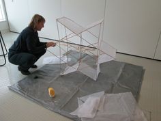 a woman kneeling down next to a sculpture on top of a piece of plastic paper