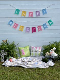 a happy easter banner on the side of a white house with flowers and decorations around it