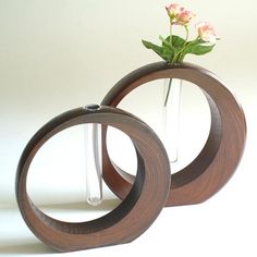 two wooden vases with flowers in them on a white surface, one is empty