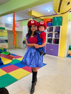 a woman and child dressed up as mario and luigi in a playroom with toys