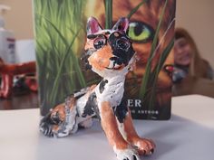 a ceramic cat figurine sitting on top of a table next to a book