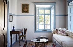 a living room filled with furniture next to a window and a painting on the wall