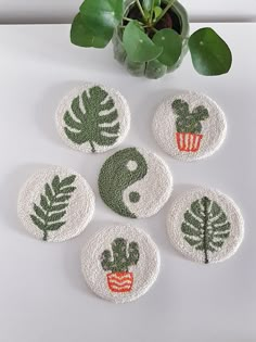 four coasters with different designs on them and a potted plant in the background