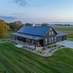 an aerial view of a house in the middle of a field with grass and trees