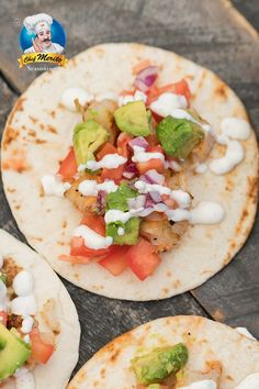 three tortillas topped with avocado, tomatoes and other toppings on a wooden table