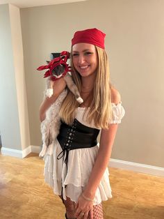 a woman in a pirate costume holding a cat and posing for the camera with her hands on her hips