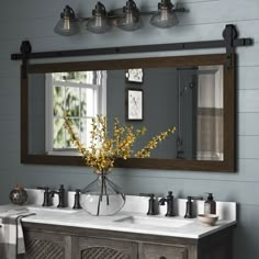 a bathroom vanity with two sinks and a large mirror over it's top, in front of a blue wall