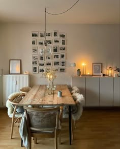 a dining room table with chairs and pictures on the wall above it, along with candles