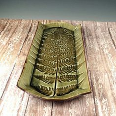 a leaf shaped dish sitting on top of a wooden table