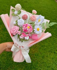 a person holding a bouquet of flowers on top of a green grass covered park area